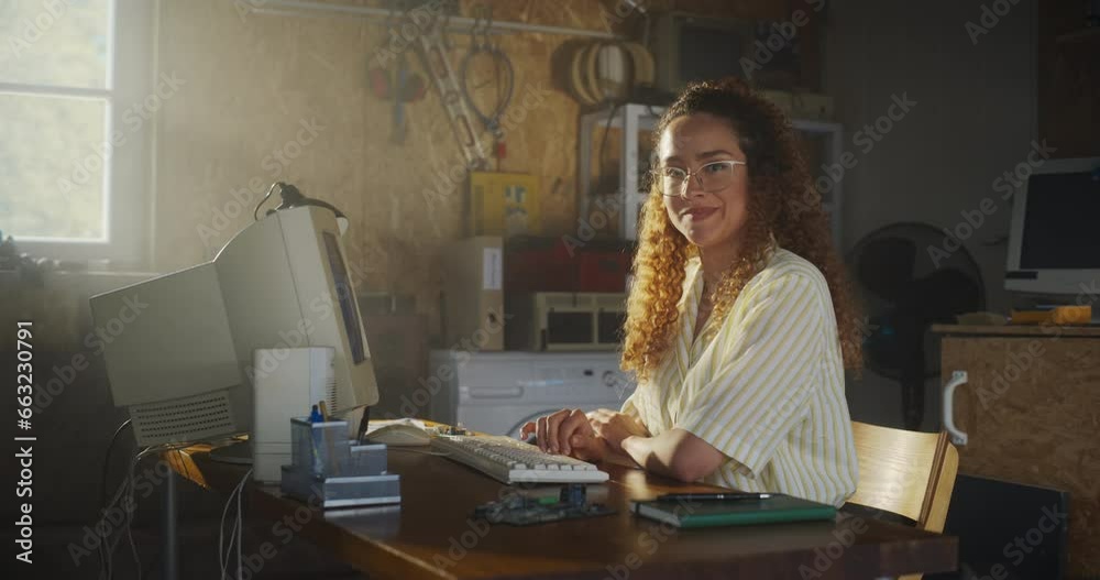 Poster Hispanic Female Software Engineer Programming On Old Desktop Computer In Retro Garage, Looking At Camera And Smiling. Woman Starting an Innovative Startup Company In Nineties. Nostalgia Concept.