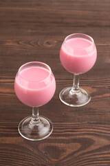 Sweet strawberry liqueur in glass on a brown wooden. side view