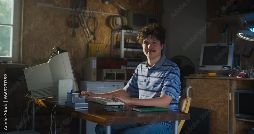 Poster Caucasian Male Software Engineer Programming On Old Desktop Computer In Retro Garage, Looking At Camera And Smiling. Man Starting an Innovative Startup Company In Nineties. Nostalgia Concept.