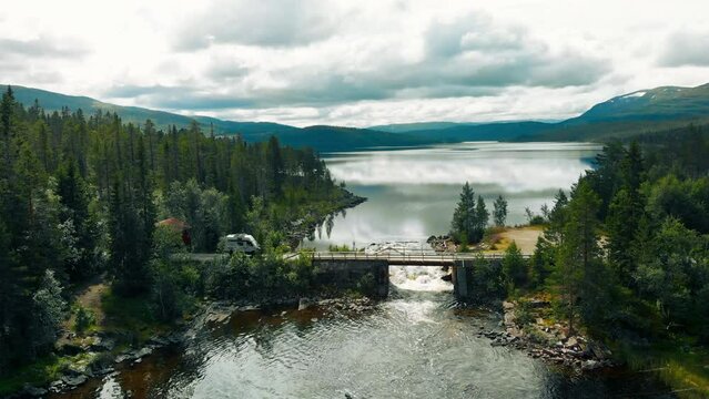 Cool offroad overlanding rig, 4x4 full drive camper van with solar panel setup drive on secluded gravel road and bridge in remote area of Canada or Norway. Camper van outdoor lifestyle