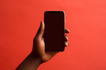 Fototapeta na wymiar Closeup of African Hand Holding Smartphone on Red Backdrop