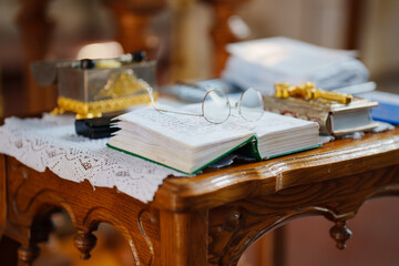 Glasses on the pages of an open Bible on a table in a church. 