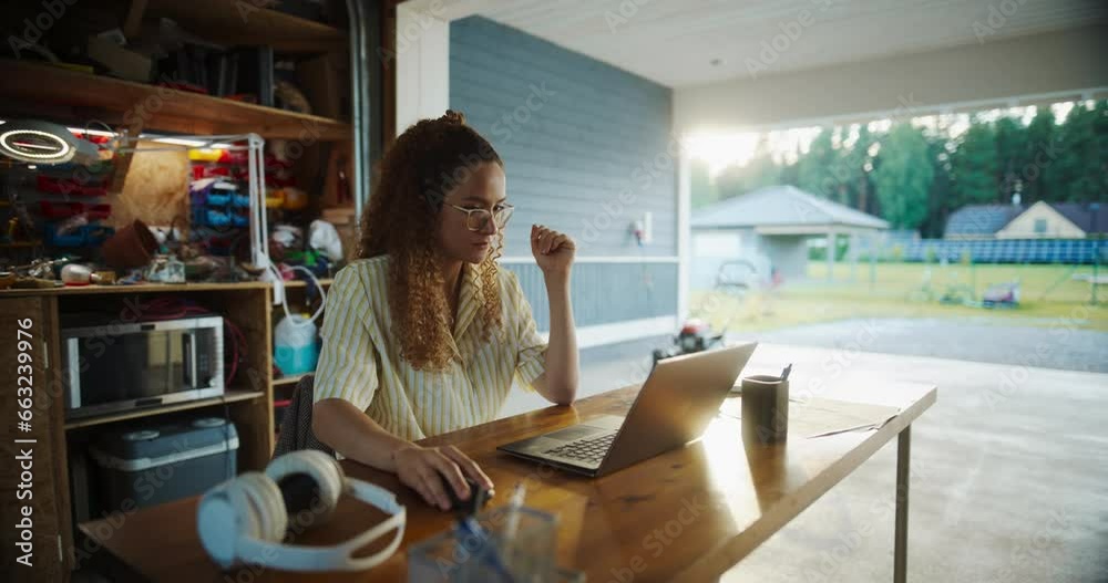 Poster Young Hispanic Female Software Engineer Programming On Laptop Computer In Opened Garage. Woman Running A Startup With Innovative SaaS Solution For Businesses. Developer Writing Code, Optimizing System