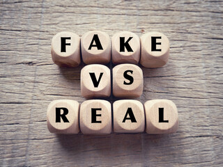 Business and financial issue concept. FAKE VS REAL written on wooden blocks. With blurred styled...