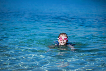 little girl plays and swims in the water in the sea