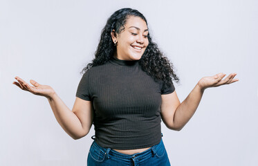 Smiling latin woman comparing with palms hands isolated. Happy girl balancing product with palms...