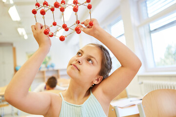 Girl holding molecular structure in classroom