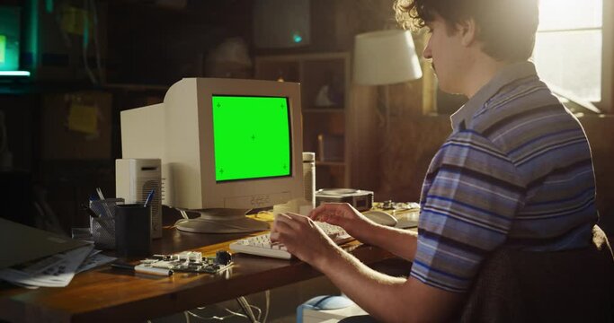 Caucasian Male Hardware Engineer Programming On Old Desktop Computer With Green Screen Chromakey On Display In Retro Garage. Software Developer Writing Code For Innovative Operating System In Nineties