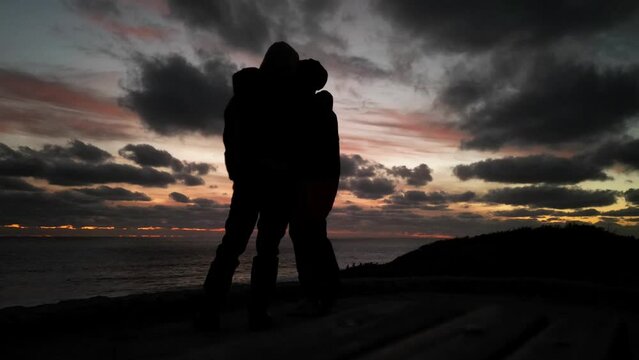 Time lapse shot showing silhouette of couple in love enjoying dramatic sunset with clouds at beach - low angle close up