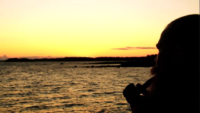 vibrant saturated scenery of waters mountains and sunset with a male smoking pipe on the side of the frame cinematic view clouds of smoke waves moving in all directions looking forward confidently