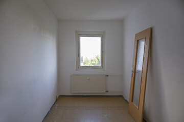 Small room in need of renovation, the door leaning against the wall, concept for affordable living...