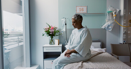 Sad, woman and thinking at window in hospital with stress, anxiety or fear of cancer, death or insurance. Senior, patient and depression in clinic with lady worried on bed for future or mental health