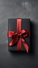 Red gift box with ribbon bow and black ribbon on black background. christmas and new year concept.