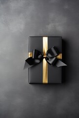 Black gift box with golden ribbon and bow on black background, top view with space for text.