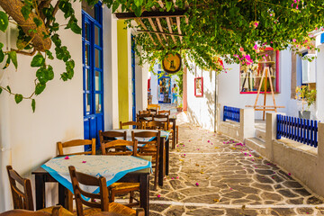 Chairs with tables in traditional Greek restaurant tavern in Plaka village, Milos island, Cyclades, Greece - obrazy, fototapety, plakaty