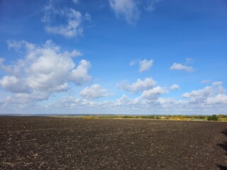 A large flat field with a blue sky and clouds