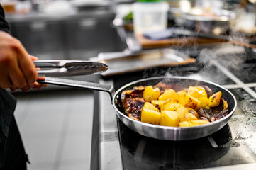 Chef cook hand cooking potato and meat food in pan at the restaurant kitchen