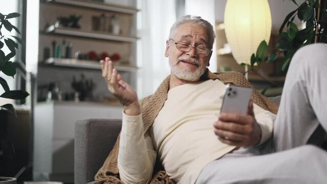 Portrait of handsome gray haired senior man having video call conference meeting by smartphone gadget at light home Smiling mature male talking on personal conversation indoors High quality 4k footage