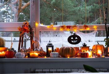 Festive decor of the house on the windowsill for Halloween - pumpkins, Jack o lanterns, skulls,...