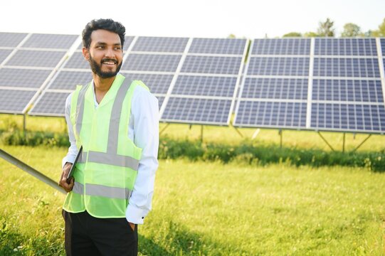 Portrait young indian technician or manager wearing formal cloths standing with solar panel. renewable energy, man standing crossed arm, copy space
