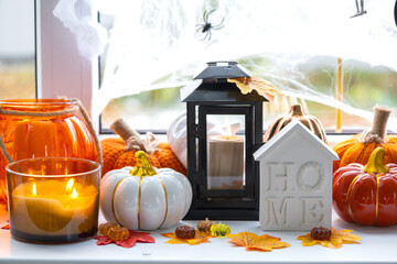 Cozy autumn decor on the windowsill with pumpkins, autumn leaves, a house and keys - autumn mood, Halloween, housing, relocation, mortgage, insurance.