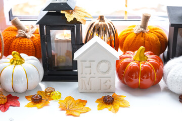 Cozy autumn decor on the windowsill with pumpkins, autumn leaves, a house and keys - autumn mood,...