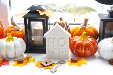 Cozy autumn decor on the windowsill with pumpkins, autumn leaves, a house and keys - autumn mood,...