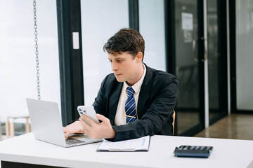 Young businessman working at office with laptop, tablet and taking notes on the paper..