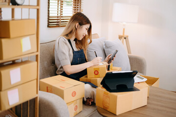 Young business owner woman prepare parcel box and standing check online orders for deliver to customer on tablet, laptop Shopping Online concept....