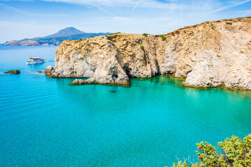 Fototapeta premium View of beautiful rocky coast near Tsigrado beach and boat on azure sea water, Milos island, Cyclades, Greece