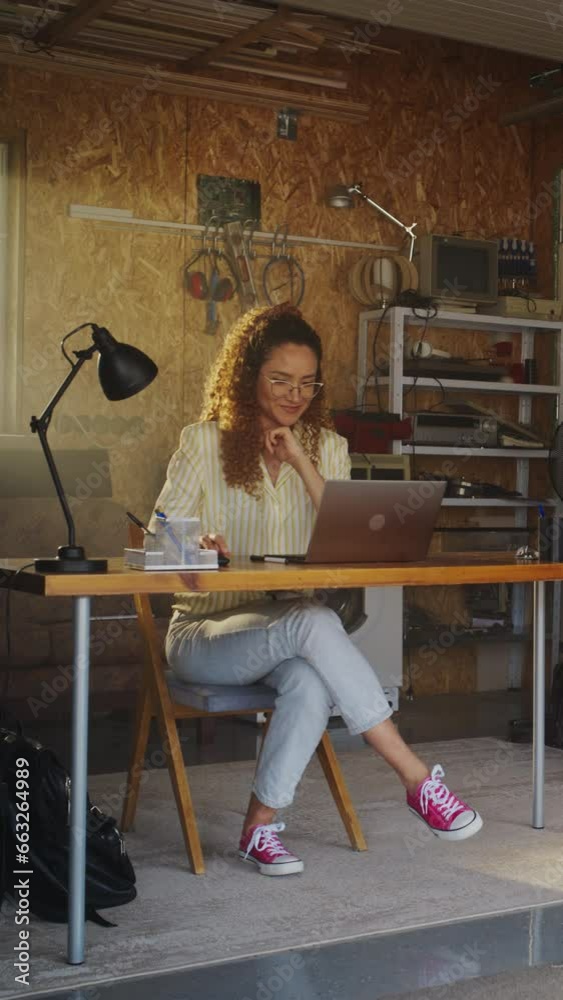 Leinwandbilder vertical screen: hispanic female programmer coding on laptop computer in garage at home. young woman