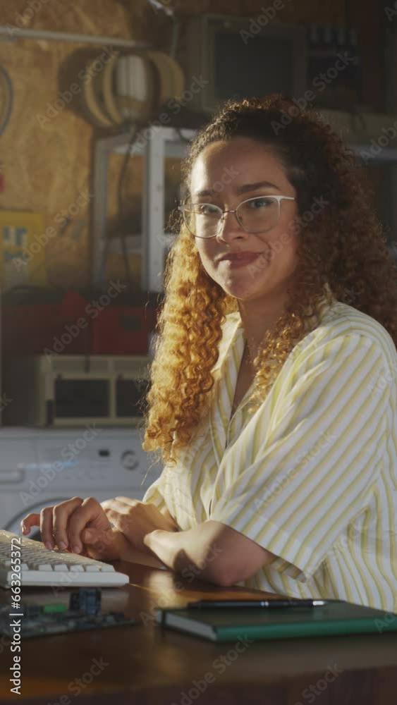 Poster Vertical Screen: Hispanic Female Software Engineer Programming On Old Desktop Computer In Retro Garage, Looking At Camera And Smiling. Woman Starting an Innovative Startup Company In Nineties.