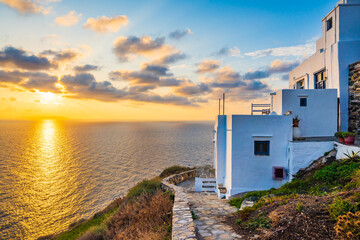 Sunrise over rocky coast of Sifnos island with typical white houses in foreground in Kastro village, Cyclades, Greece