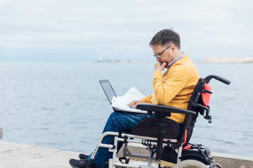 a special person with disabilities by the sea with a laptop