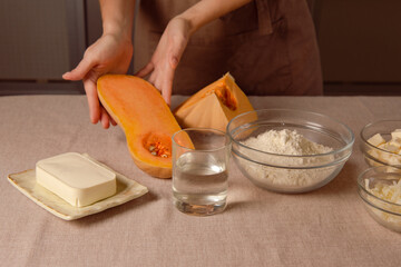 baked pumpkin recipe for homemade cooking. woman chef in brown kitchen apron hold sliced pumpkin ready to cook