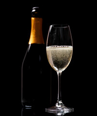 Champagne glass and bottle on a black