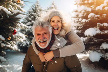 happy smiling portrait of an old couple wearing warm clothes and having fun in winter forest