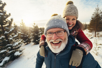 happy smiling portrait of an old couple wearing warm clothes and having fun in winter forest