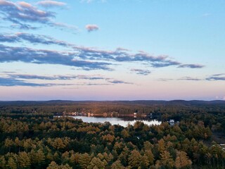 Fototapeta na wymiar aerial of lake in the distance surrounded by trees during sunset