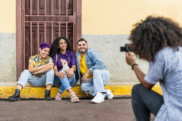 man with afro hair taking pictures in the street of his friends from the lgbt community