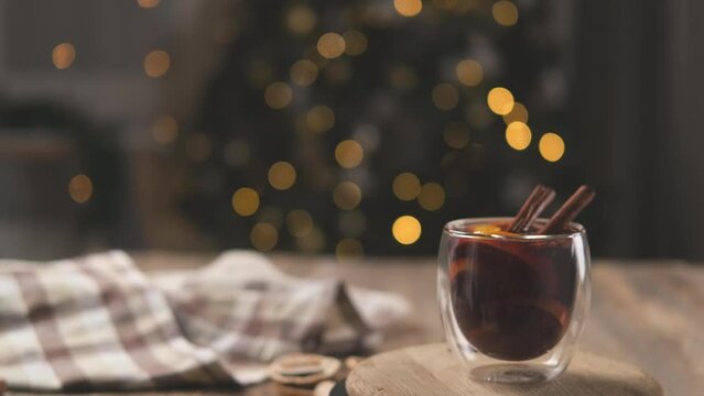 Double bottom glass filled with mulled wine on wooden board on christmas tree background