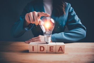 Businesswoman in green suit hand touch light bulb on wooden blocks cubes text  