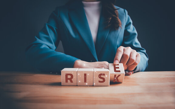 Businesswoman hand flipping wooden blocks cubes text between "RISE" and "RISK" on table. Risks assessment. Business risk management and growth performance. Planning strategies and achieving goals.
