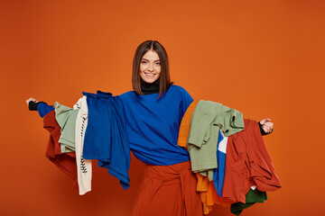happy woman with brunette short hair holding colorful autumnal clothes,  black friday concept
