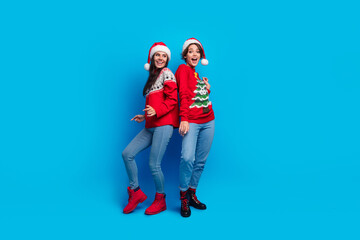 Full length photo of positive pretty ladies santa helpers dressed print sweaters enjoying xmas...