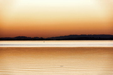 Fototapeta na wymiar impression of lake chiemsee with golden shining light at the evening
