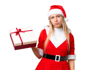 Young blonde woman with christmas hat and holding a gift over isolated chroma key background with sad expression