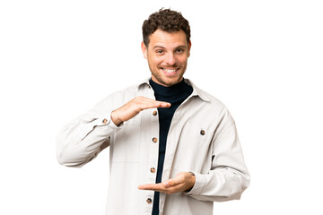 Brazilian man over isolated chroma key background holding copyspace imaginary on the palm to insert...