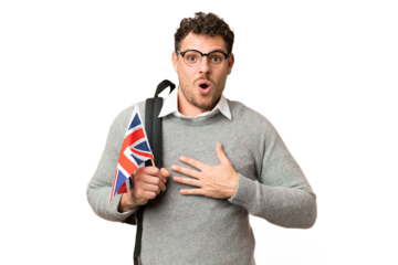 Brazilian man holding an United Kingdom flag over isolated chroma key background surprised and shocked while looking right