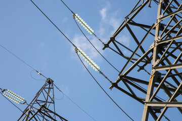 High voltage tower with electrical voltage wires isolates close-up against the background of clouds. Energy industry.